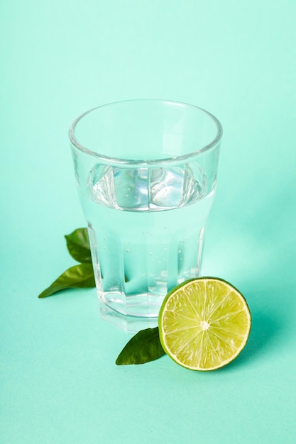 Verre D'eau Citron Vert Et Feuilles Sur Fond De Menthe