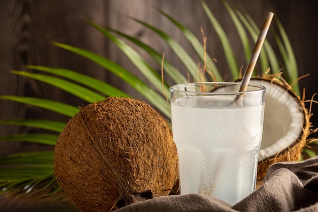 Verre avec de l'eau de coco fraîche et des noix de coco sur la table