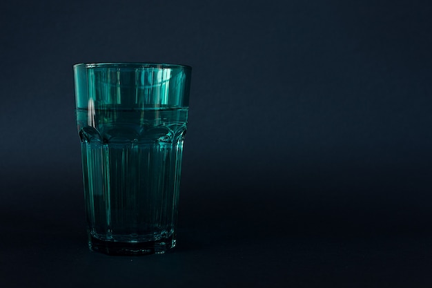 Verre d'eau coloré sur fond sombre.