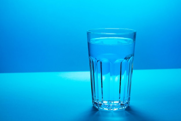 Un verre avec de l'eau dans un fond de couleurs bleues