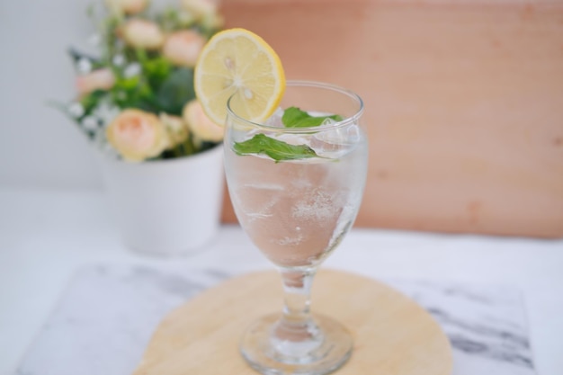 Un verre d'eau avec du citron et de la menthe sur une table en bois