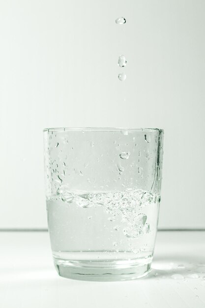 Un verre d'eau avec des éclaboussures sur fond blanc en studio