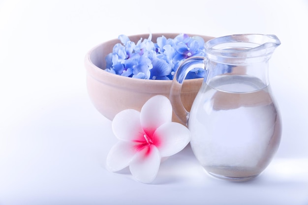 Un verre d'eau et une fleur sur fond blanc