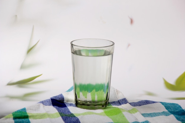 verre avec de l'eau et un fond clair avec des feuilles de plantes