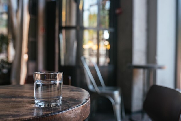 Verre d'eau sur fond flou de table en bois