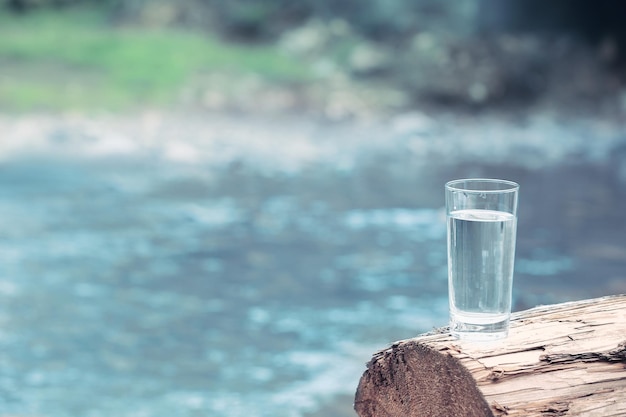 Verre d'eau sur fond de rivière floue