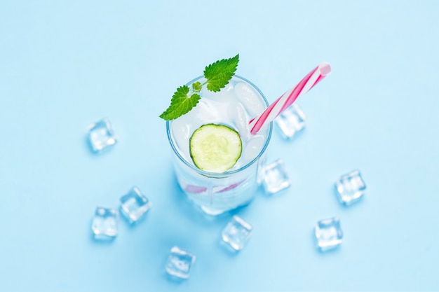 Verre D'eau Froide Et Rafraîchissante Avec De La Glace, De La Menthe Et Du Concombre Sur Fond Bleu. Glaçon. Concept D'été Chaud, Alcool, Boisson Rafraîchissante, étancher La Soif, Bar. Mise à Plat, Vue De Dessus