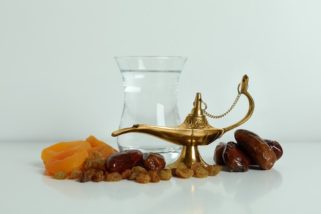 Verre d'eau, fruits secs et lampe Ramadan sur surface blanche