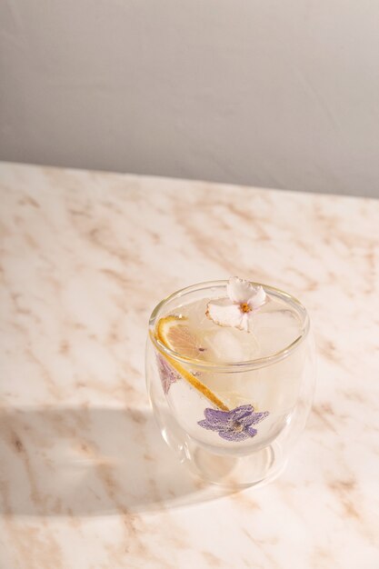 Un verre d'eau glacée décoré de fleurs sur table en marbre