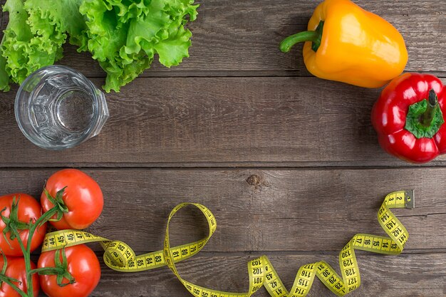 Verre d'eau avec des légumes et ruban à mesurer sur table libre