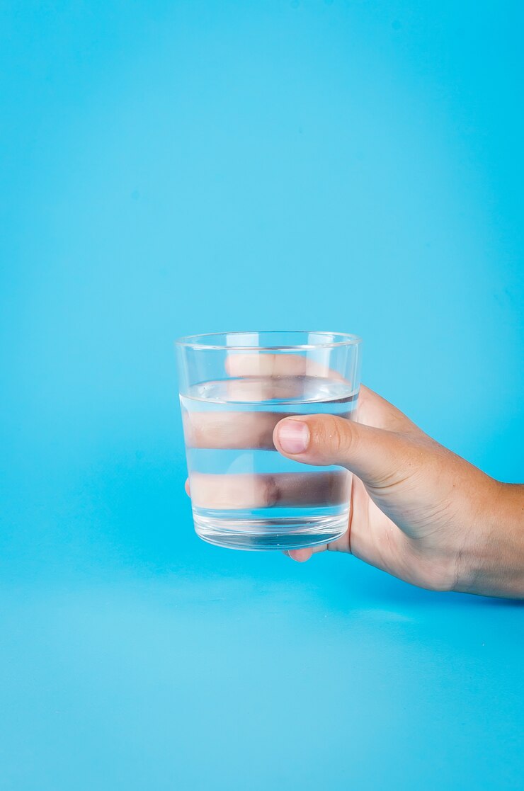 Verre d'eau à la main sur bleu