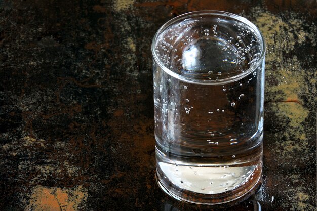 Photo un verre d'eau minérale potable sur une surface humide.