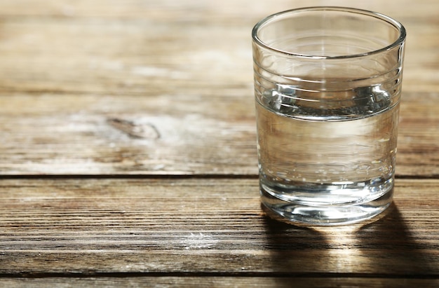 Verre d'eau minérale propre sur fond de planches de bois rustique