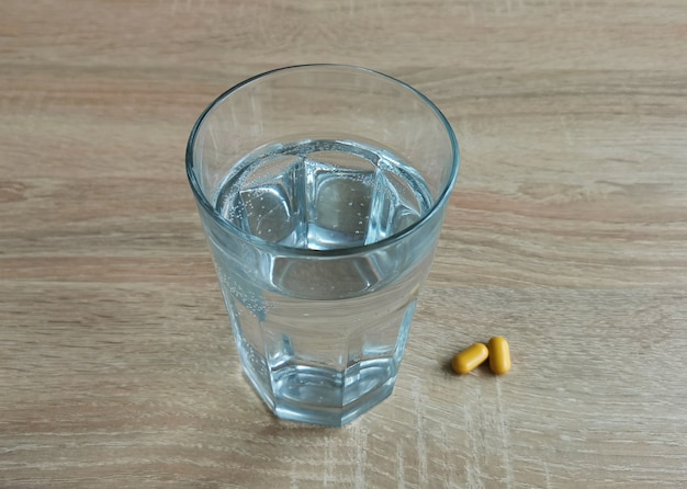 Verre d'eau et pilules sur une table en bois