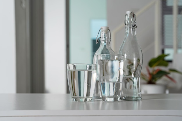 Un verre d'eau potable et une bouteille d'eau Sur une table en bois blanc