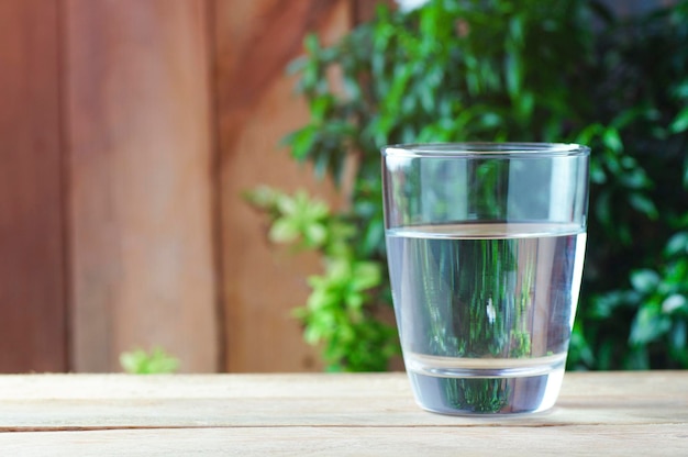 Photo verre d'eau potable sur fond de bois et de nature verte