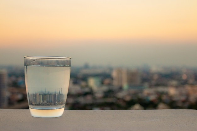 Un Verre D'eau Potable Sur Un Fond De Ville Floue, Concept De Santé.