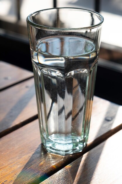 Un verre d'eau sur une table en bois, de l'eau propre à boire.