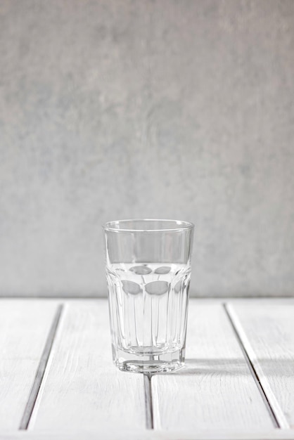 Un verre d'eau sur une table avec un fond gris.