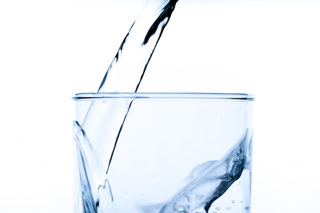 Verre d'eau avec verser de la bouteille, tourné en studio