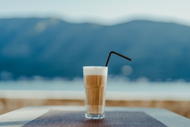 Verre à facettes avec café latte et paille.