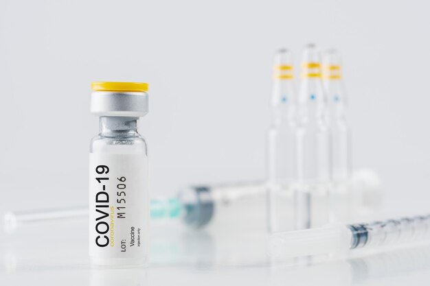 Verre de flacon de vaccin contre le coronavirus avec une seringue sur tableau blanc
