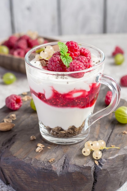 Verre avec framboises, granola et yaourt disposés en couches agrandi.