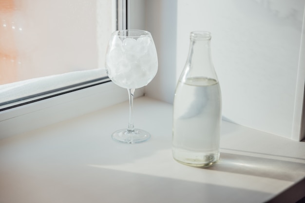 Un verre avec de la glace et une bouteille d'eau