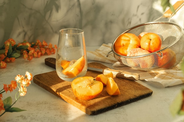 Un verre avec de la glace et des fruits frais nectarine et pêche pour faire une limonade de boisson froide