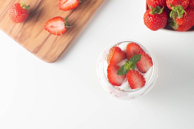 Verre avec granola, yaourt et fraises fraîches sur tableau blanc. Concept de bol de petit-déjeuner sain.
