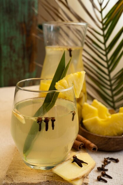 Un verre de jus d'ananas avec des bâtons de cannelle sur le côté.