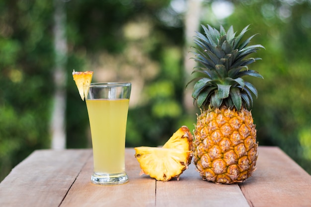 verre de jus d&#39;ananas avec fond de nature verdoyante