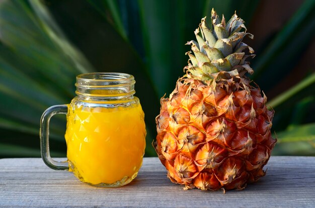 Verre de jus d'ananas frais et de fruits d'ananas mûrs sur une table en bois rustique.Jus d'ananas fraîchement pressé avec de la paille à boire.Aliments sains, régime alimentaire ou concept de nourriture végétalienne.