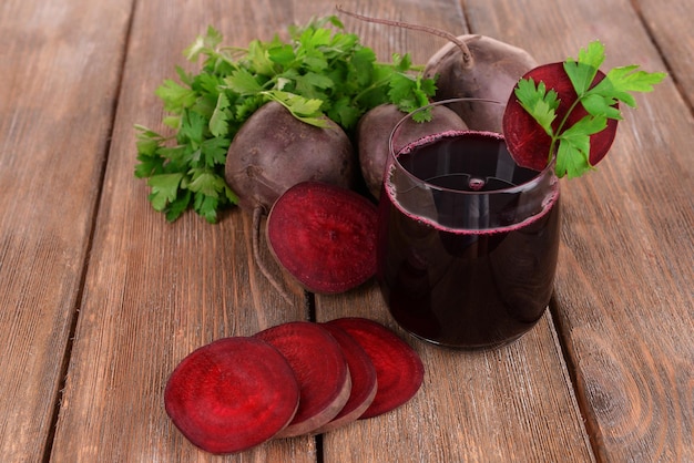 Verre de jus de betterave frais et de légumes sur fond de bois