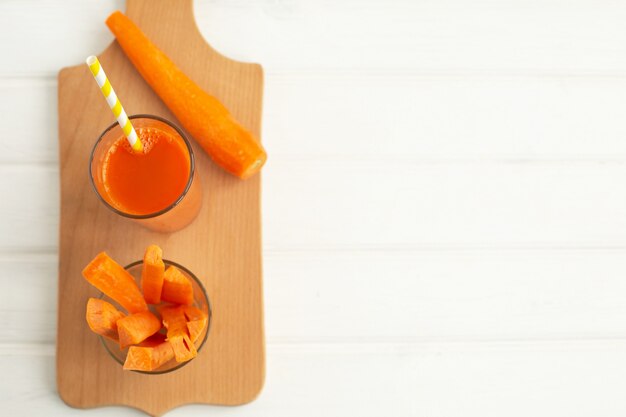 Verre de jus de carotte et de carotte fraîche sur une planche à découper