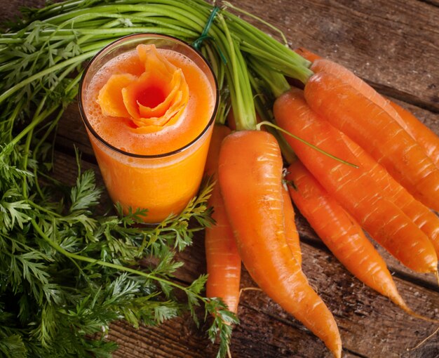 Verre de jus de carottes fraîches avec carottes biologiques fraîches
