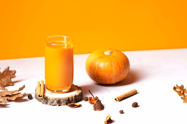 Un verre de jus de citrouille ou de smoothie se dresse sur une coupe en bois