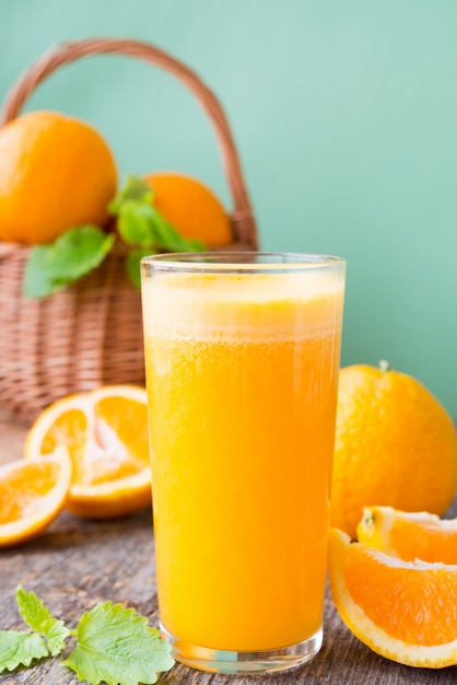 Un verre de jus fraîchement pressé entouré d'oranges fraîches et de mandarines. Photo verticale.