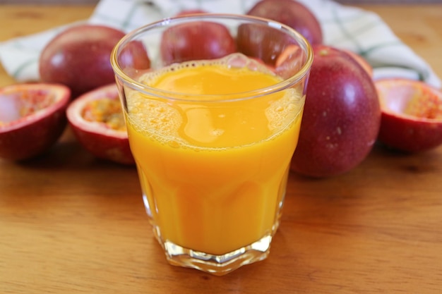 Verre de jus de fruit de la passion frais appétissant avec tas de fruits entiers en toile de fond