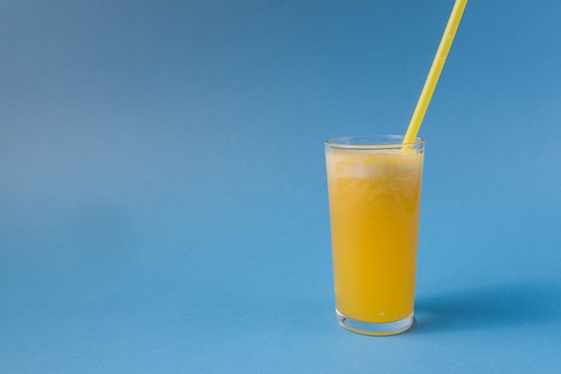 Verre de jus de fruits d&#39;ananas isolé sur fond bleu.