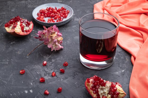 Verre de jus de grenade sur fond de béton noir avec textile rouge.