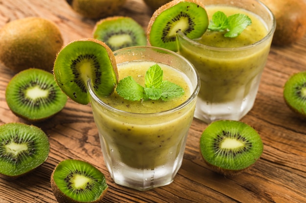 Verre de jus de kiwi avec fruits frais sur table en bois