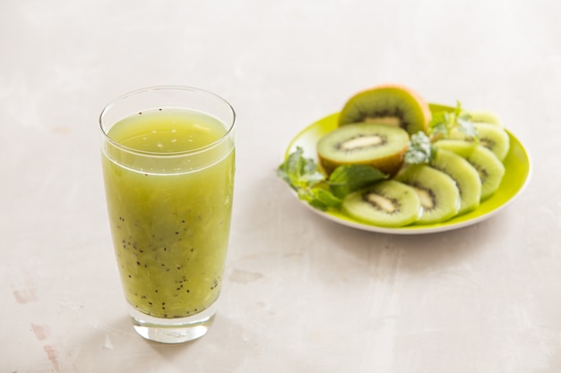 Verre de jus de kiwi avec fruits frais sur table