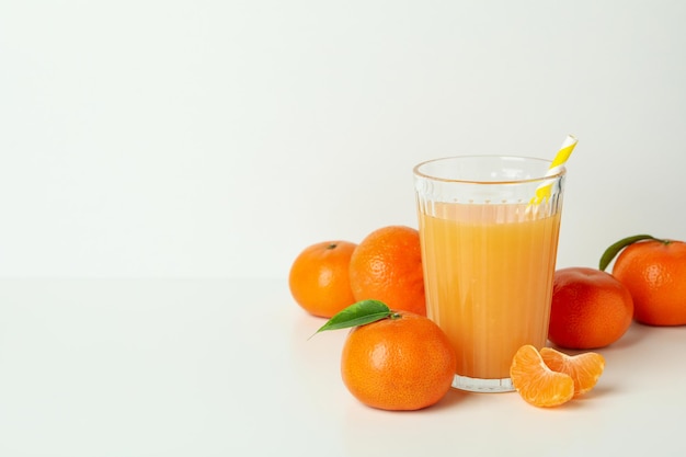 Verre de jus de mandarine et ingrédients sur fond blanc