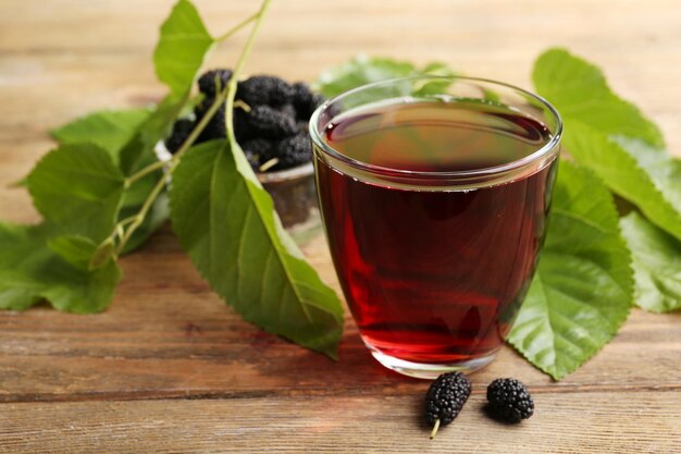 Verre de jus de mûrier rafraîchissant avec des baies sur la table en gros plan