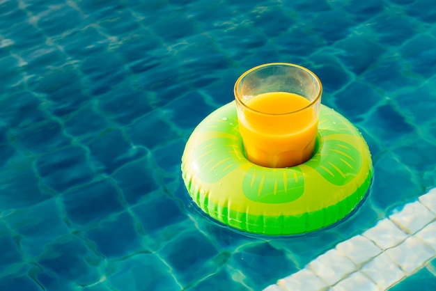 Verre de jus d'orange avec anneau de natation à la piscine extérieure