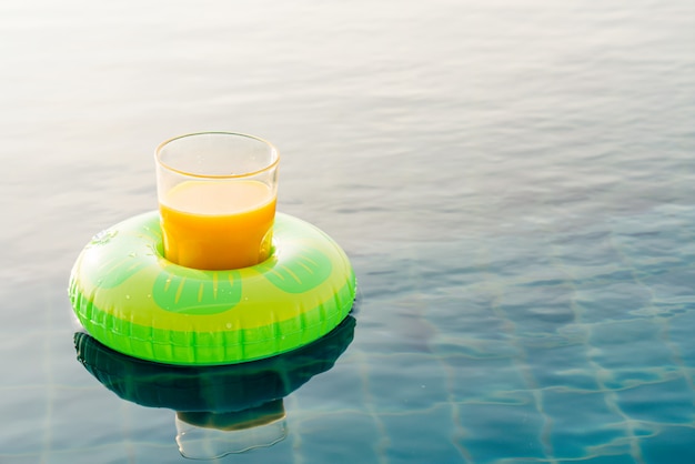Verre de jus d'orange avec anneau de natation à la piscine extérieure