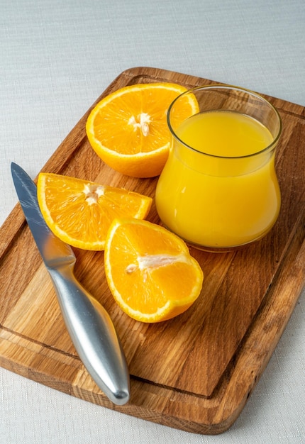 Un verre de jus d'orange et un couteau sur une planche à découper en bois