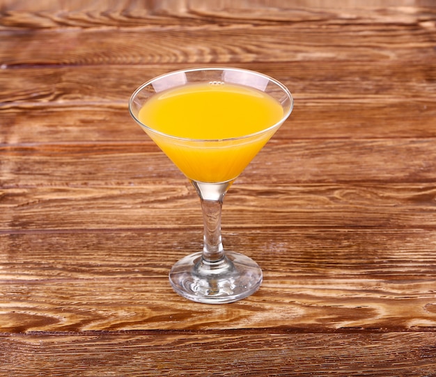 Verre de jus d'orange fraîchement pressé avec la moitié d'orange en tranches sur la table en bois