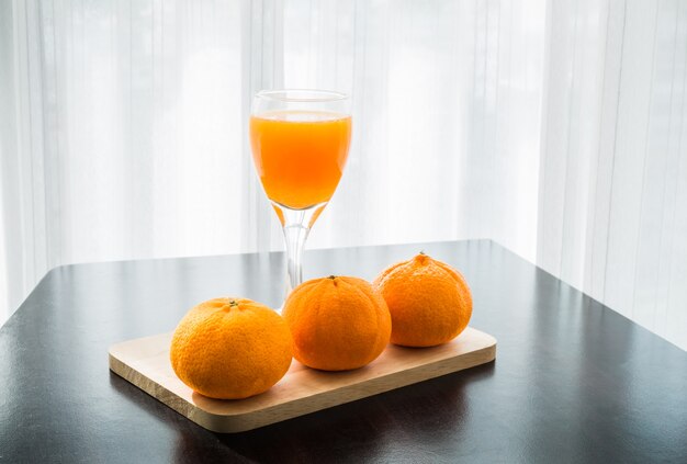 Verre de jus d&#39;orange fraîchement pressé avec trois oranges